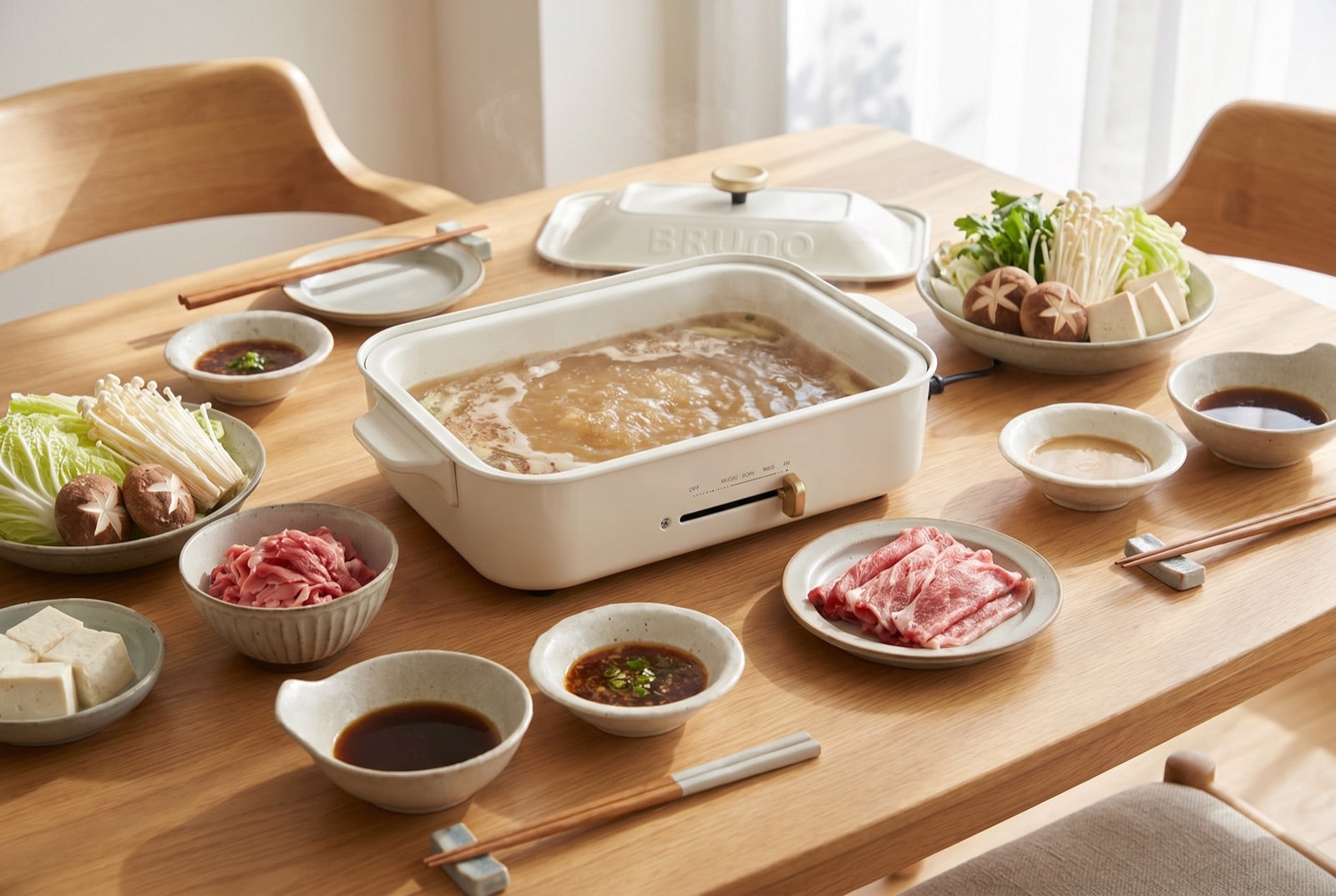 BRUNO Compact hot plate with a Japanese hotpot spread on a dining table