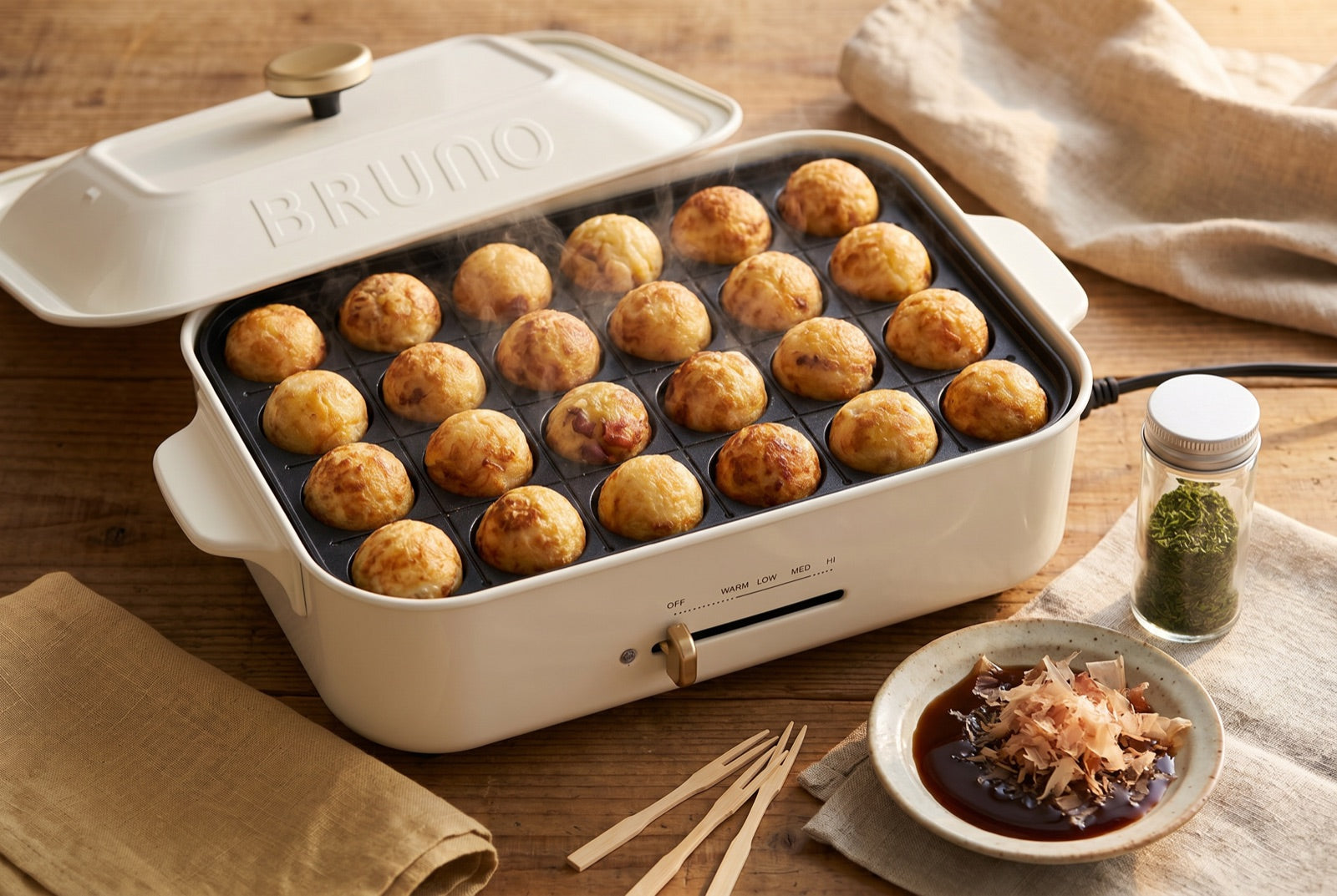 Golden takoyaki octopus balls cooking on a BRUNO takoyaki plate